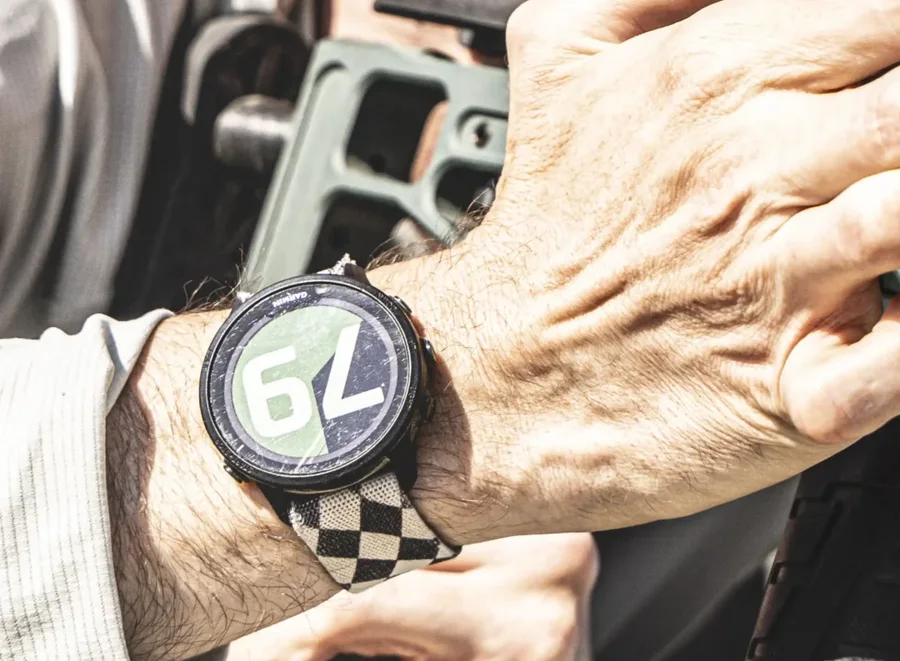 Close-up of a Garmin watch on a shooter's wrist showing 79 seconds remaining, both hands still on the rifle.